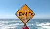 yellow and black road sign near sea during daytime